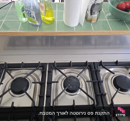 כיריים עם בקבוקי חומרי ניקוי ועגבניות בקערה ירוקה